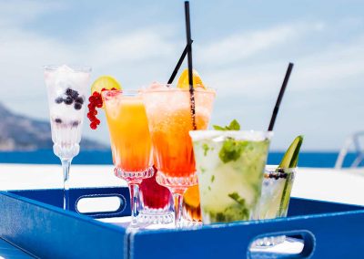 Various fruity drinks served on a blue tray, on the top deck of a yacht.