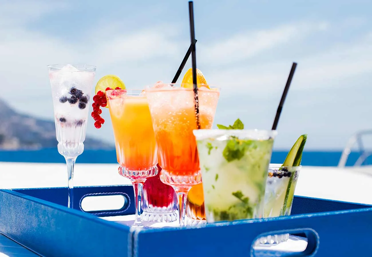 Various fruity drinks served on a blue tray, on the top deck of a yacht.