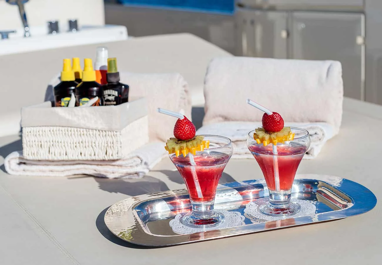Two drinks served on a silver tray, on the top deck of a yacht